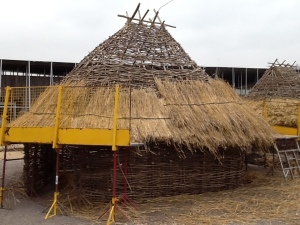 A second layer of thatch being added, held on by hazel sways.